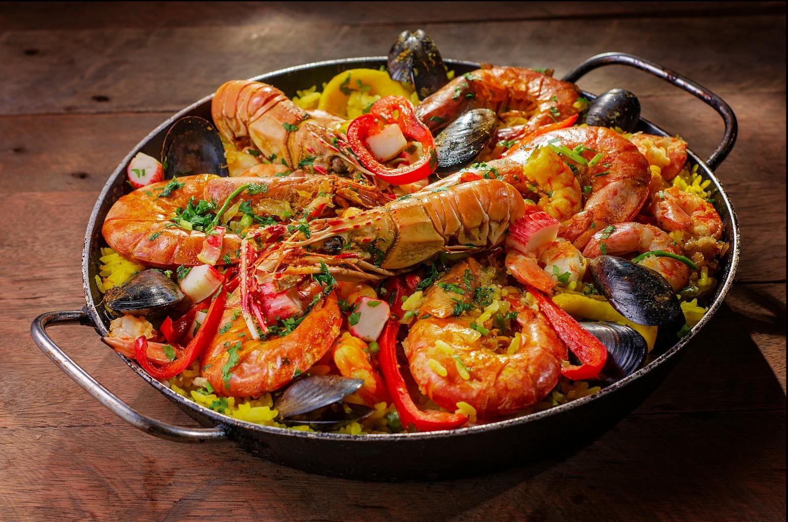 A vibrant and flavorful seafood paella served in a pan with mussels and shrimp.